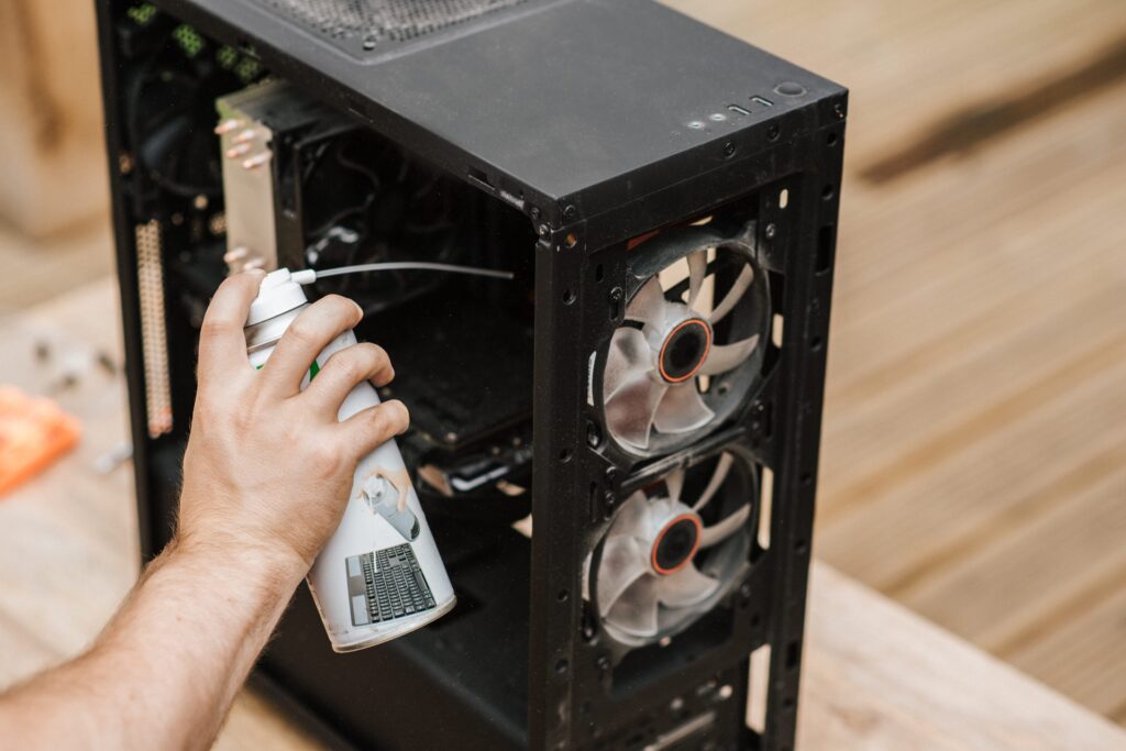 a person cleaning his pc with compressed can of air